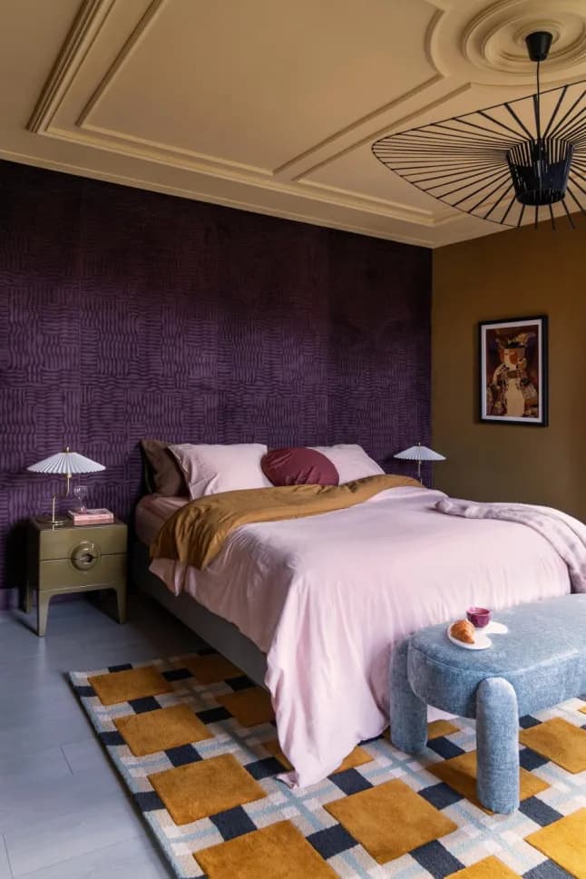 Slaapkamer met paarse wand van Arte-behang met reliëf en een geblokt vloerkleed