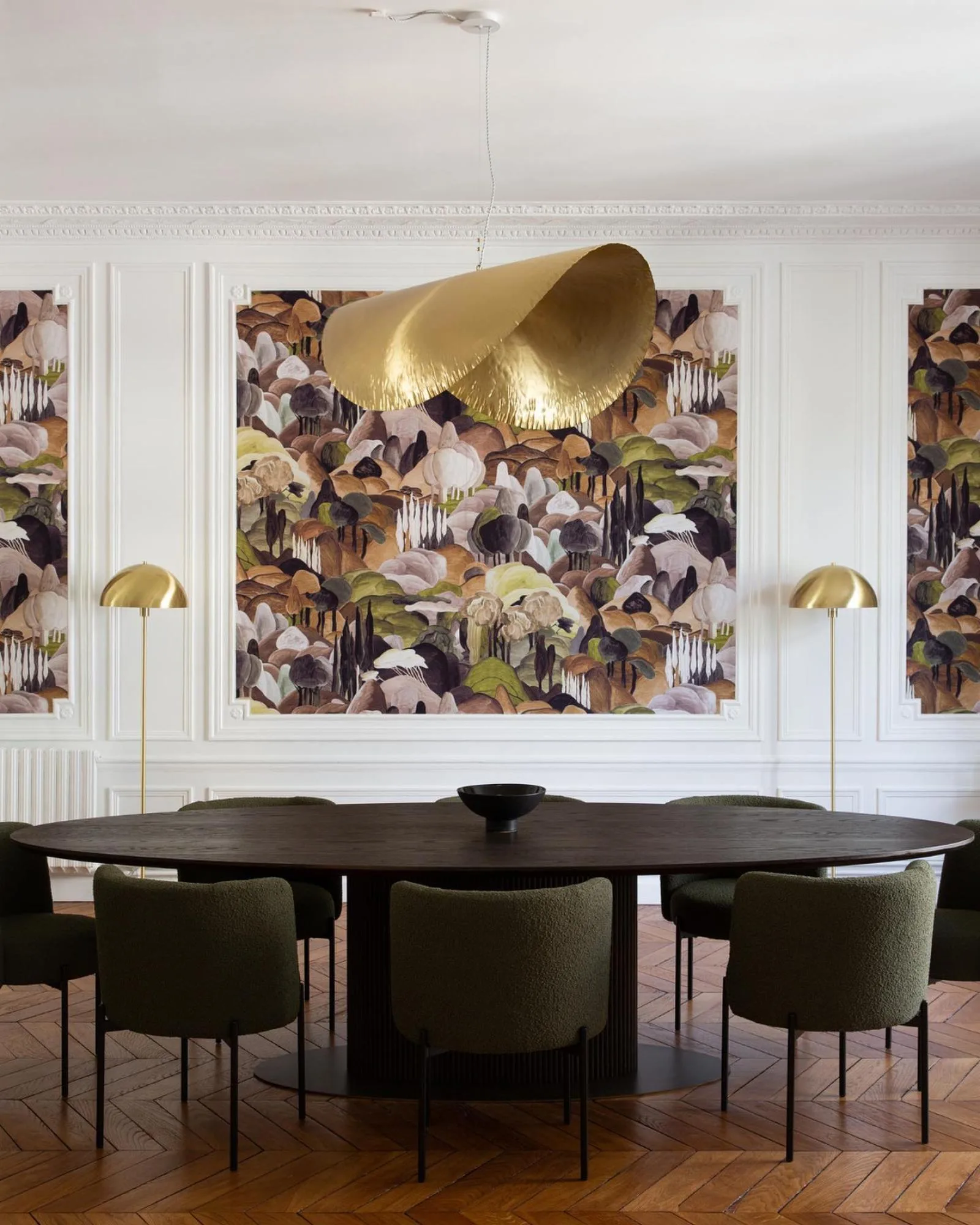 Ovale eettafel onder een gouden hanglamp, met Arte-behang in paarse en groene tinten