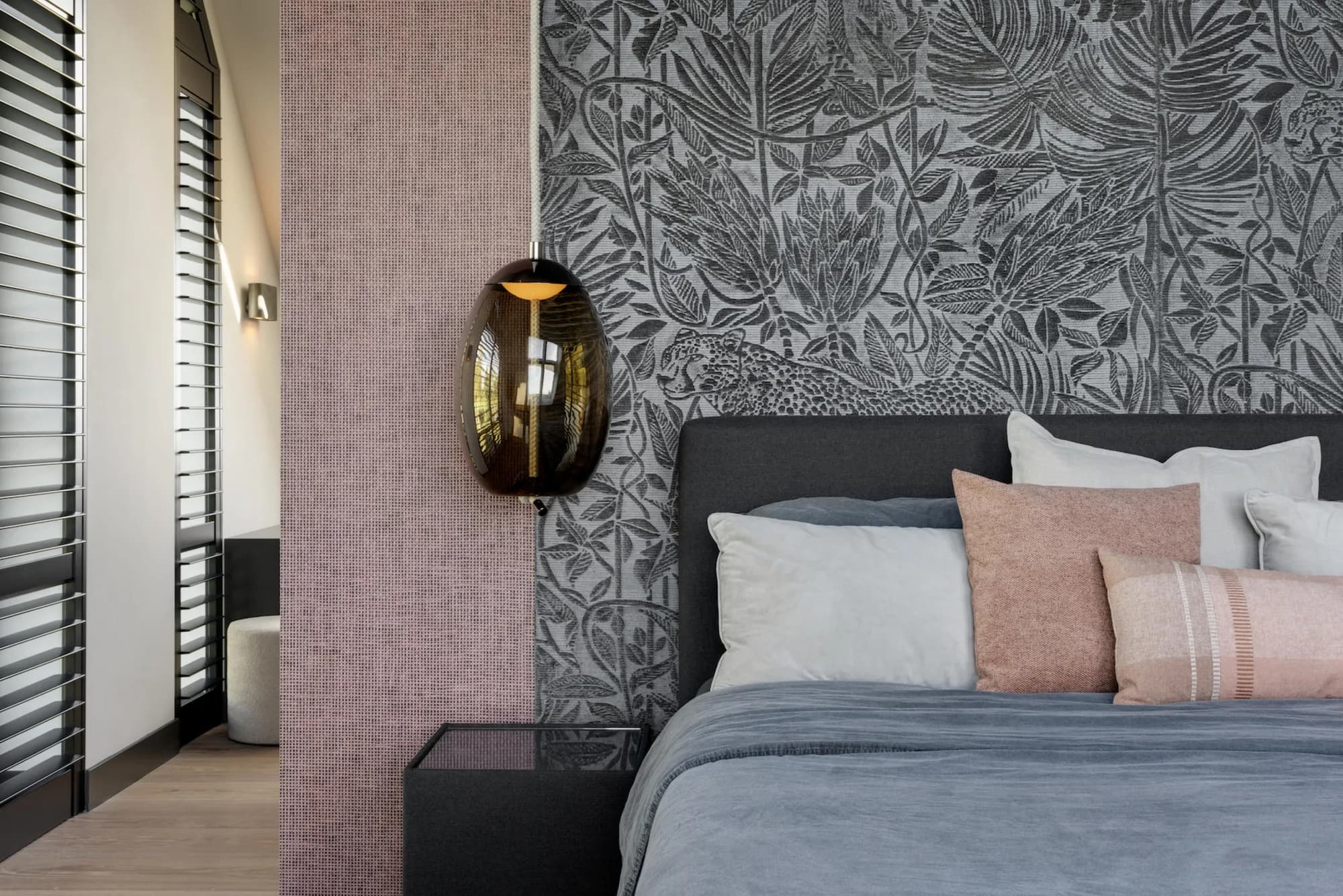 Slaapkamer met een wand van grijs Arte-behang met bladmotief naast oudroze