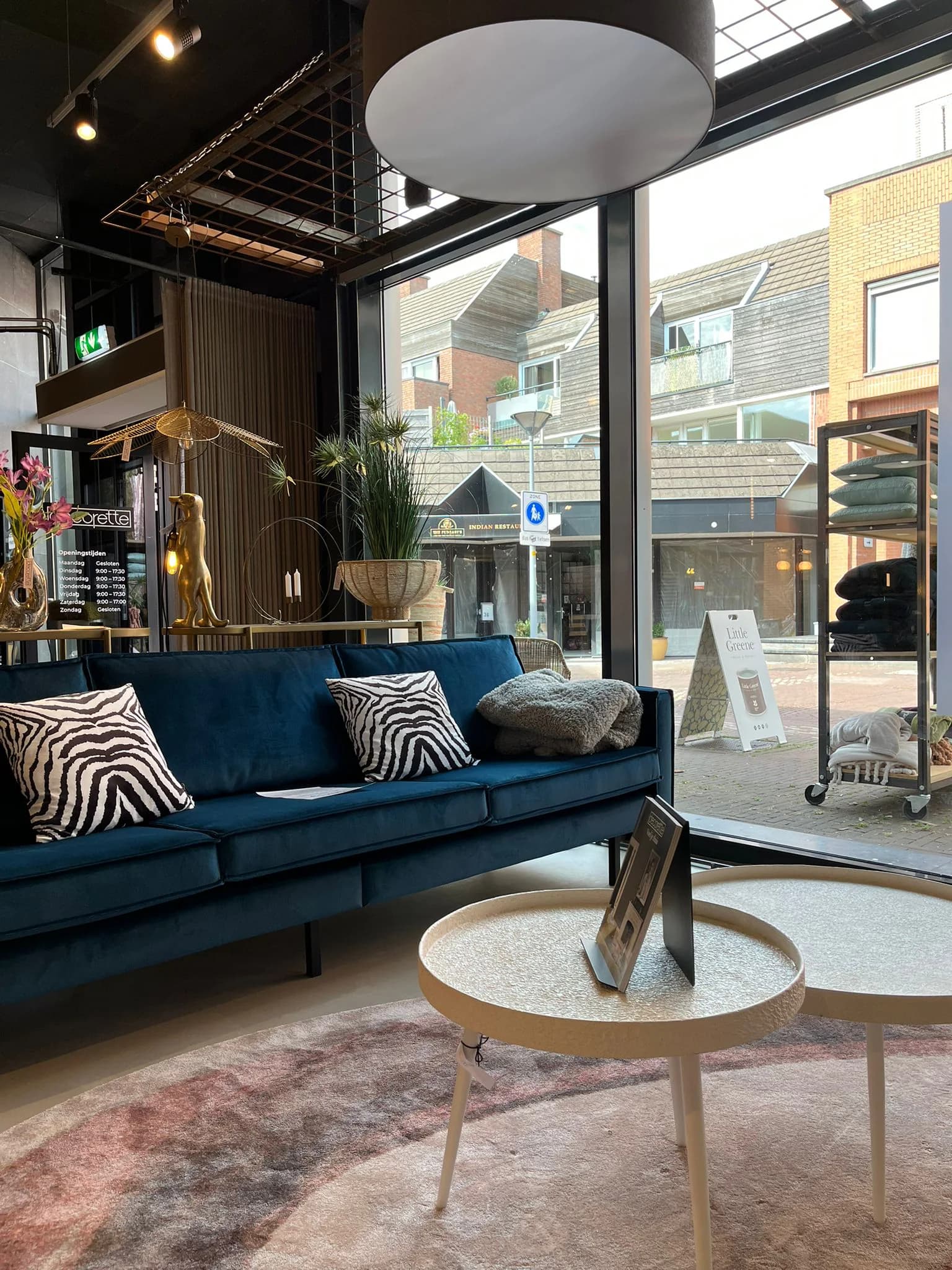 Zithoek met blauwe bank en zebrakussens bij de etalage