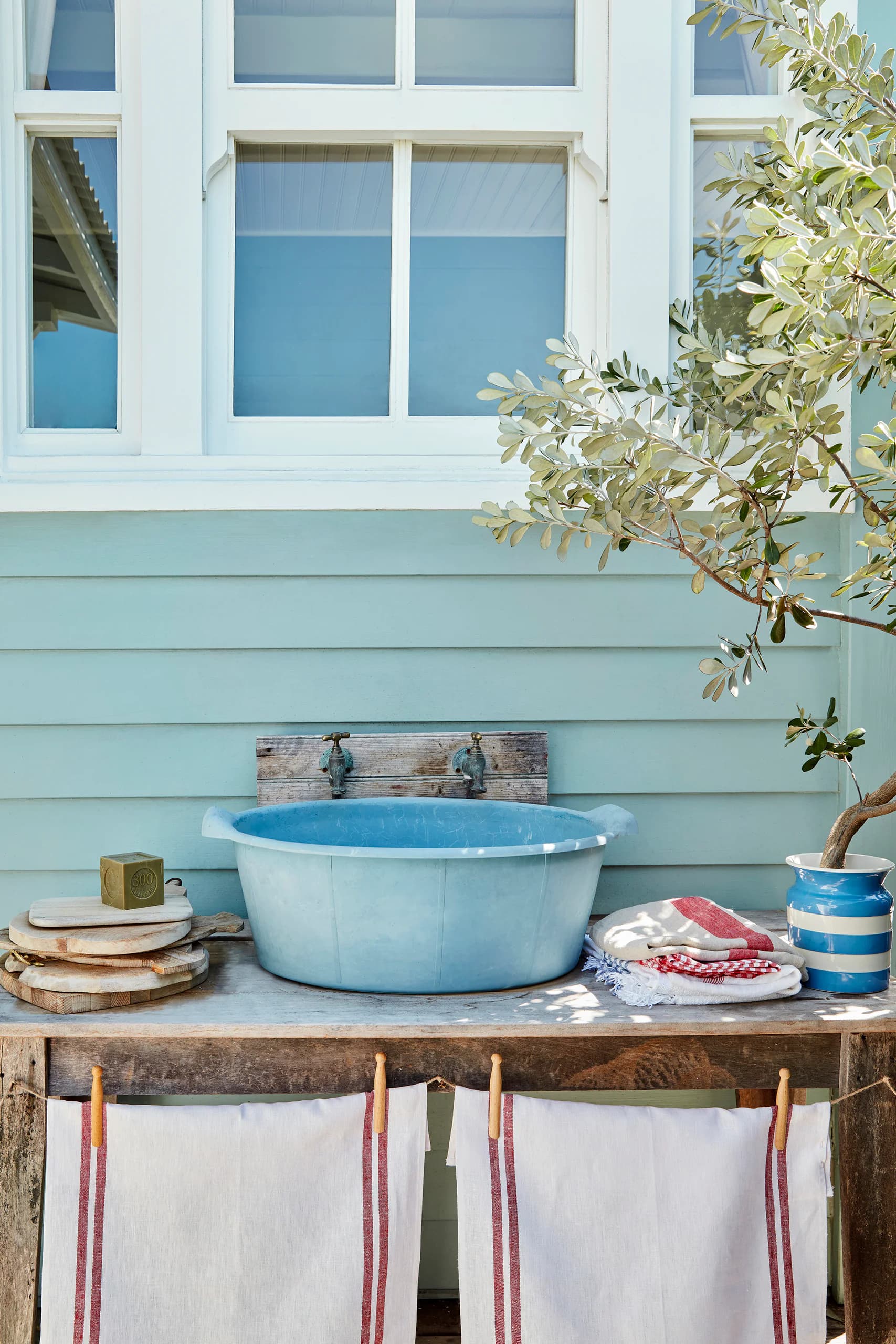 Lichtblauwe houten gevel (Celestial Blue) met witte deur (Loft White) en tuintafel