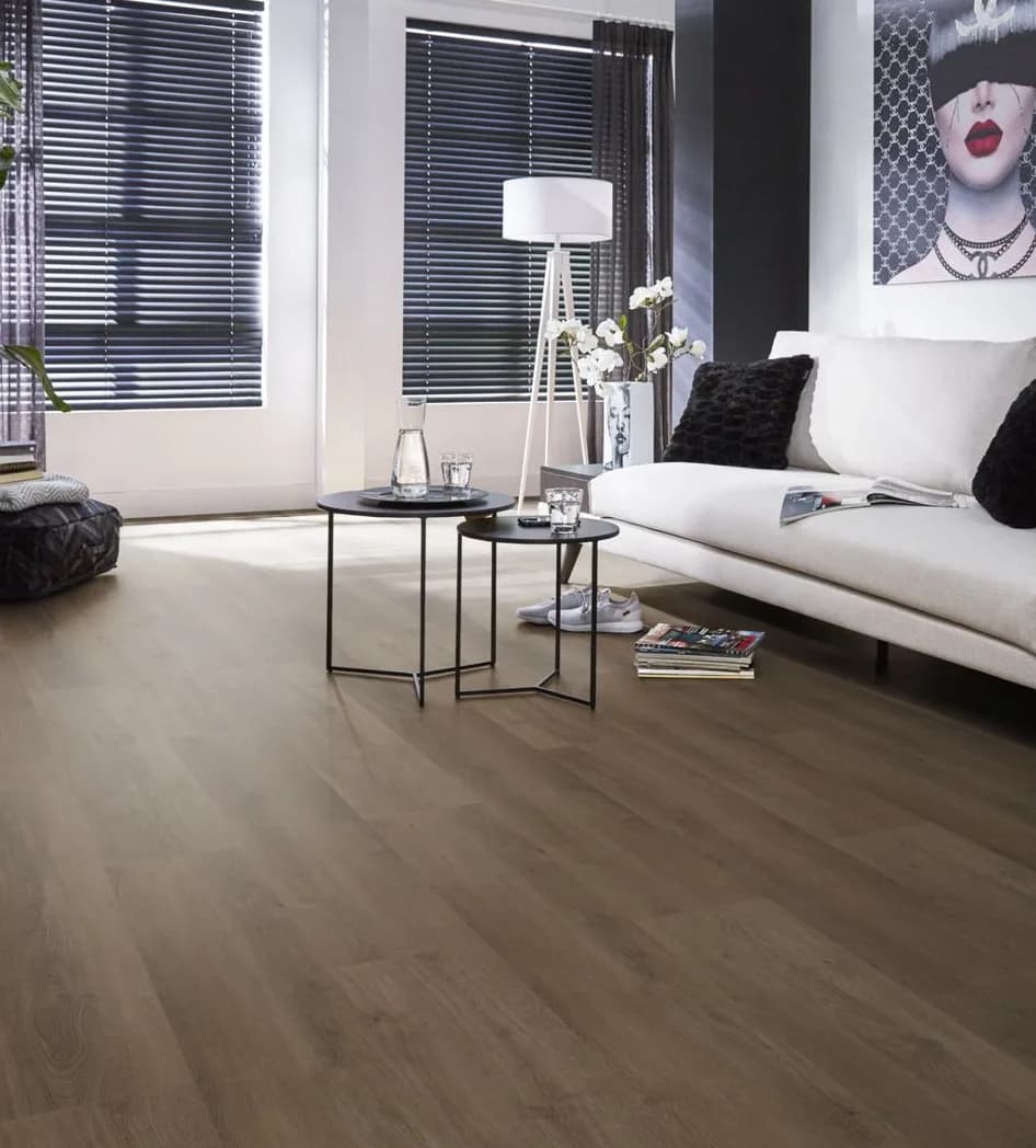 Pvc-vloer in middenbruine houtlook van Ambiant in een woonkamer met een witte bank