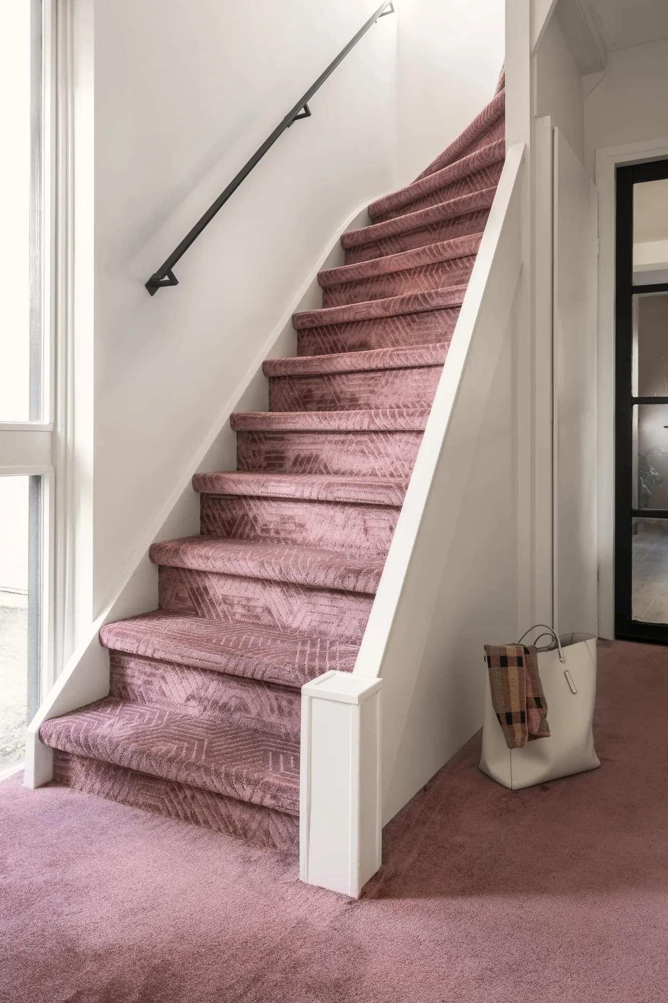 Trap met roze tapijt van Ambiant met een geometrisch patroon, aansluitend op roze tapijt in de hal