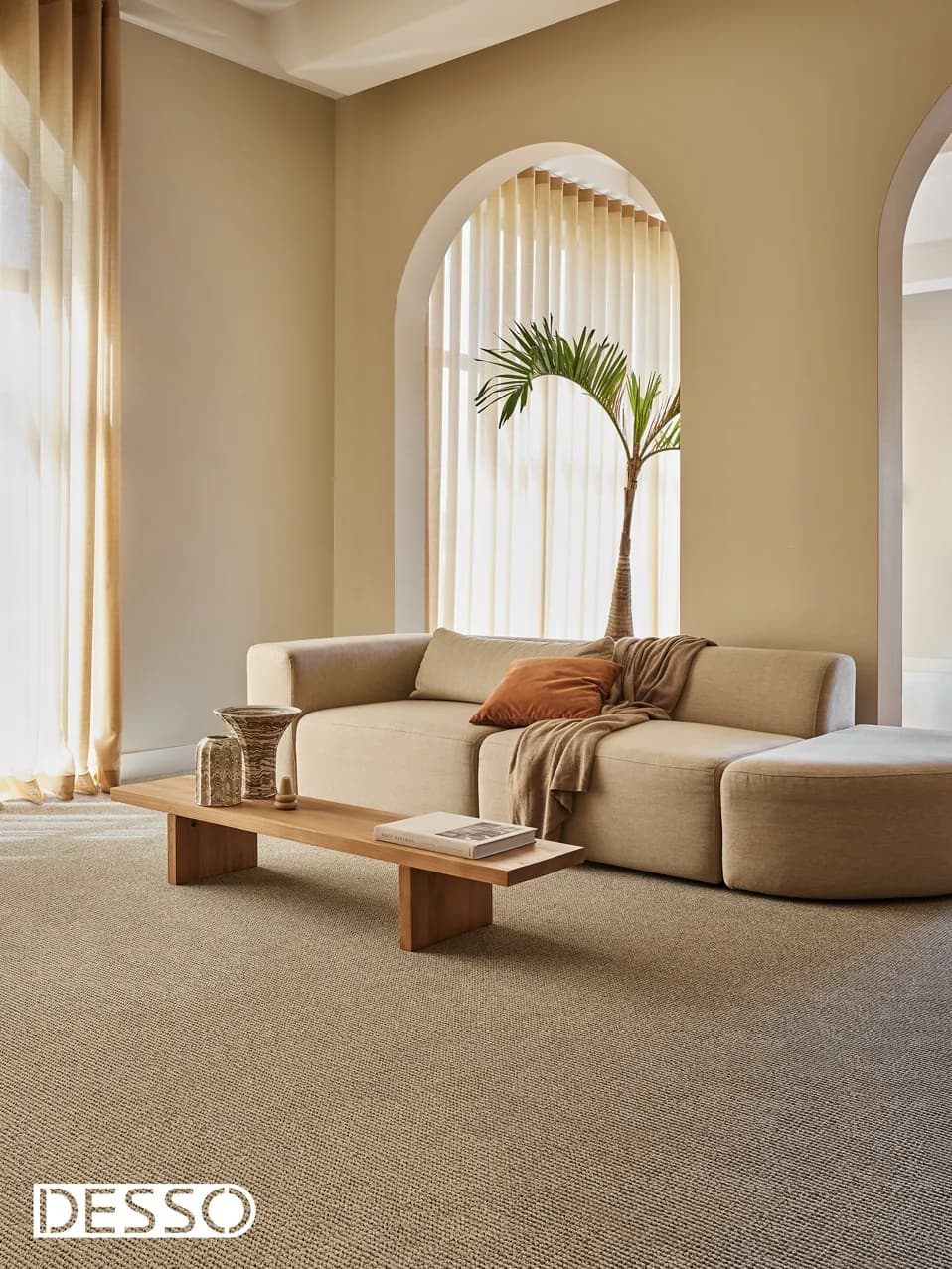 Woonkamer met een ronde bank, boogramen en beige tapijt van Desso