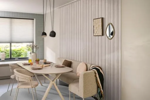 Lichte wandpanelen van Ambiant langs een eethoek met een ronde tafel